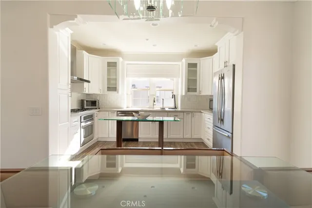 a kitchen with stainless steel appliances granite countertop a refrigerator a stove and a wooden floors