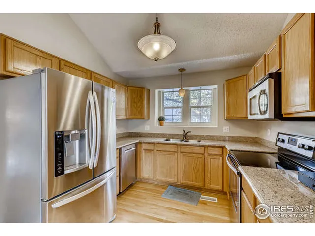 a kitchen with stainless steel appliances granite countertop a refrigerator a stove a sink and a microwave