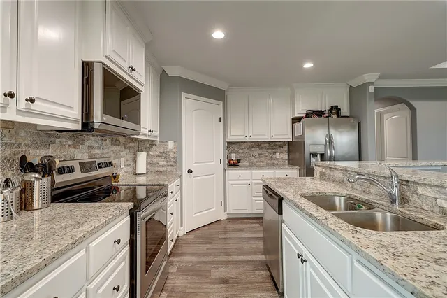 a kitchen with granite countertop a sink stainless steel appliances and cabinets