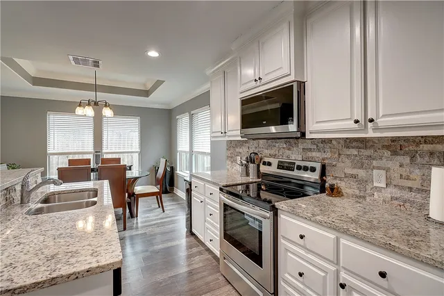 a kitchen with granite countertop a sink a counter space appliances and cabinets