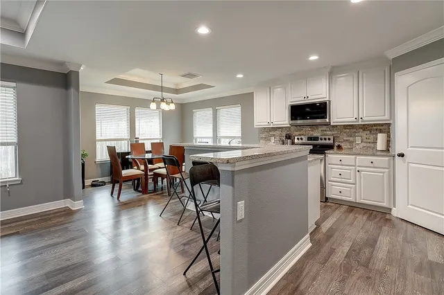 a kitchen with stainless steel appliances a white table chairs and a refrigerator