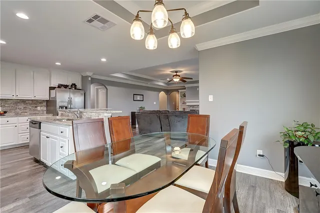 a dining room with wooden floor a chandelier a wooden table and chairs