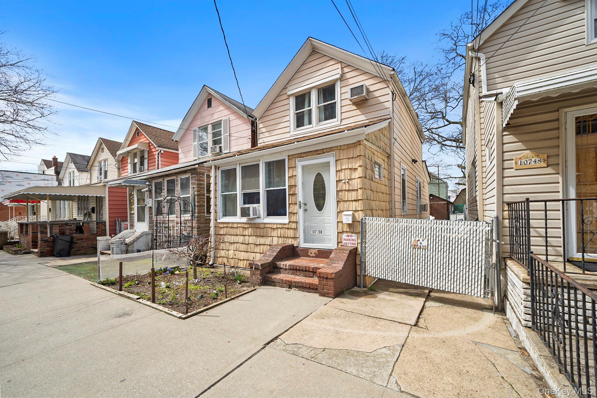 107-50 90th Street Queens, NY 11417 - Photo 2 of 9 a view of a white house with large windows and a table and chairs