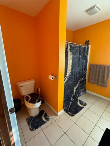 a view of a refrigerator in kitchen and an empty room with wooden floor