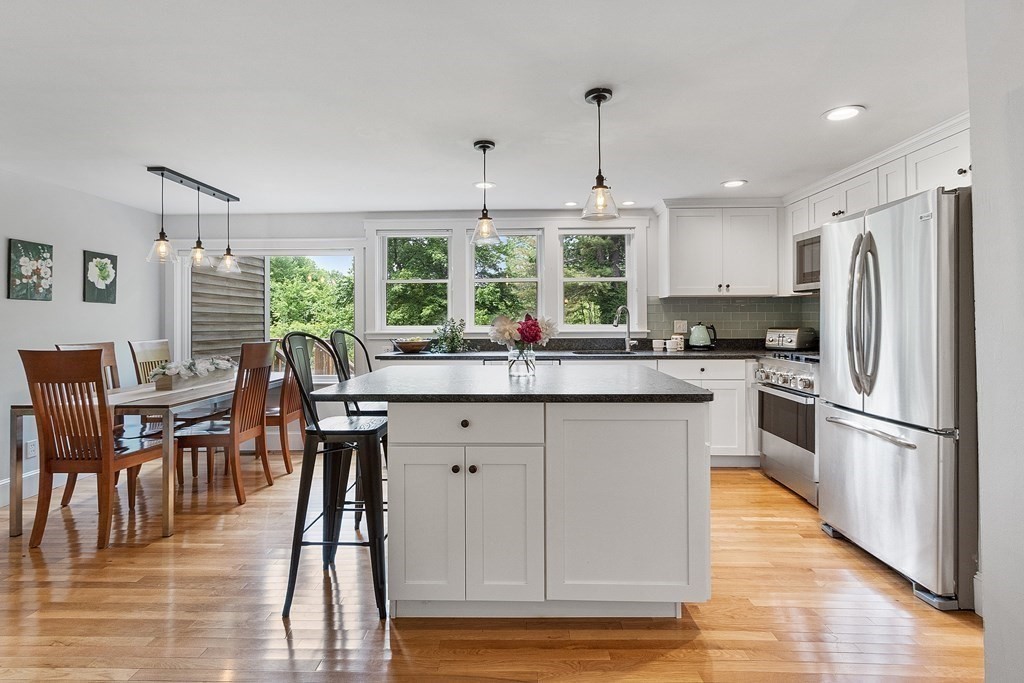 41 Gleasondale Road Stow, MA 01775 - Photo 3 of 42 a kitchen with stainless steel appliances granite countertop a stove a refrigerator a sink dishwasher a dining table and chairs with wooden floor