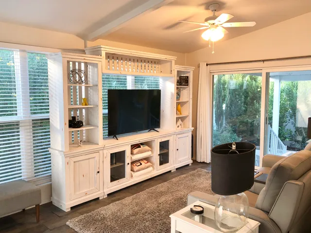 a living room with furniture a flat screen tv and a floor to ceiling window