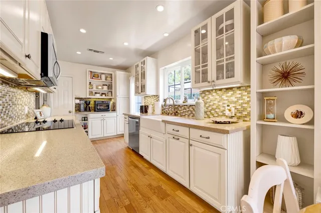 a large white kitchen with stainless steel appliances granite countertop a lot of counter space and a wooden floor