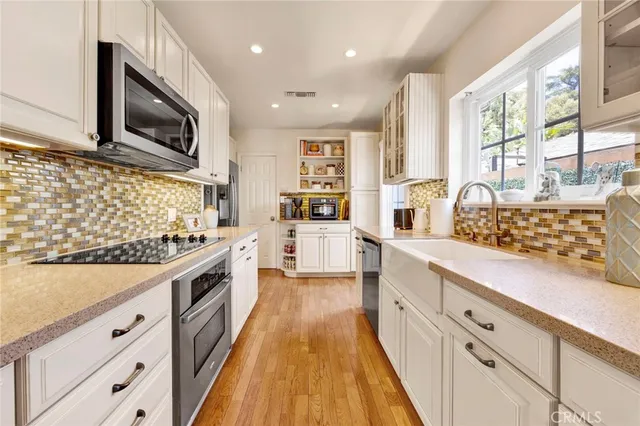 a large kitchen with stainless steel appliances granite countertop a lot of counter space and wooden floors