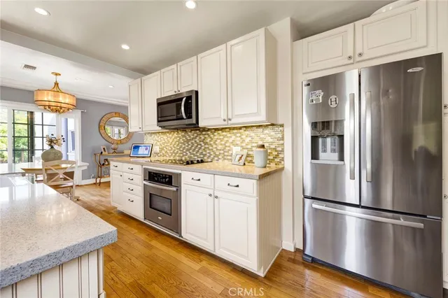 a kitchen with stainless steel appliances granite countertop a refrigerator a stove microwave and a sink