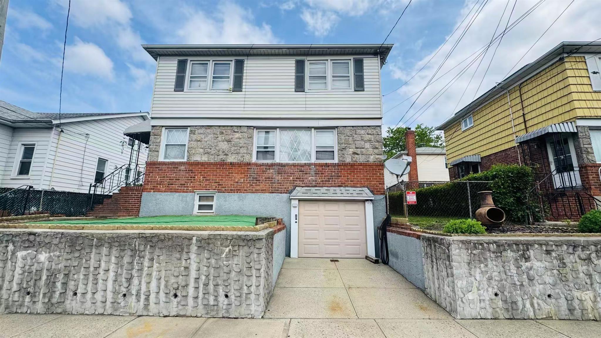View of front facade with a garage, driveway, and brick siding