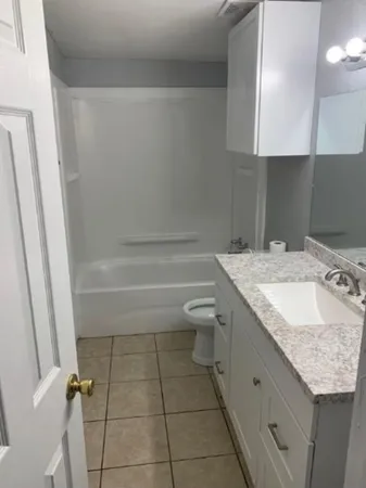 a bathroom with a granite countertop sink a toilet and shower