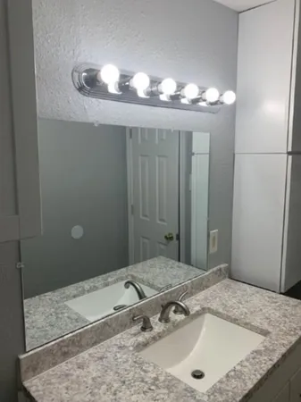 a bathroom with a granite countertop sink and a mirror