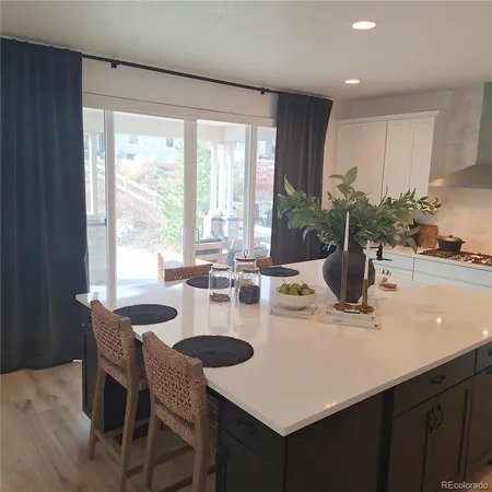 a kitchen with stainless steel appliances granite countertop a table chairs and a refrigerator