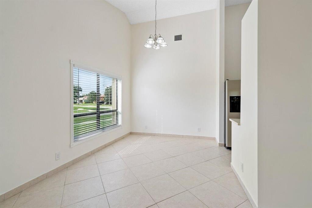 9398 Laurel Green Drive Boynton Beach, FL 33437 - Photo 7 of 19 a view of an empty room with a fireplace and chandelier