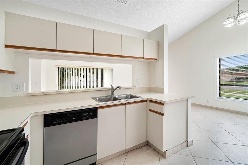 9398 Laurel Green Drive Boynton Beach, FL 33437 - Photo 8 of 19 a kitchen with stainless steel appliances granite countertop a sink and a stove next to a window