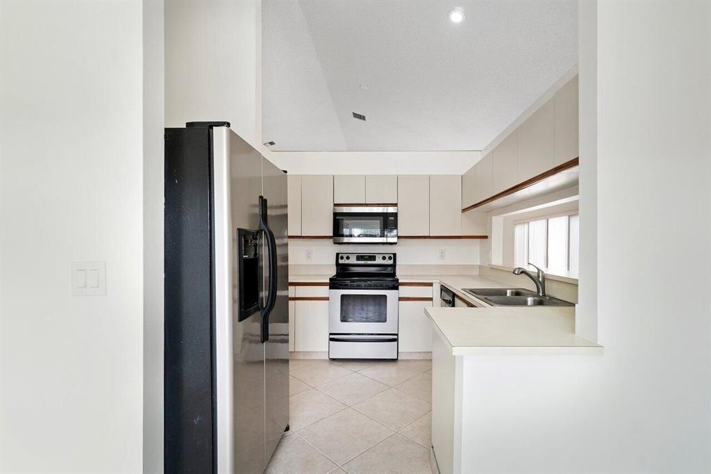 9398 Laurel Green Drive Boynton Beach, FL 33437 - Photo 10 of 19 a kitchen with stainless steel appliances a stove a microwave and a refrigerator