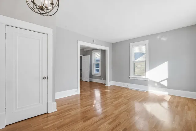 a view of an empty room with window and wooden floor