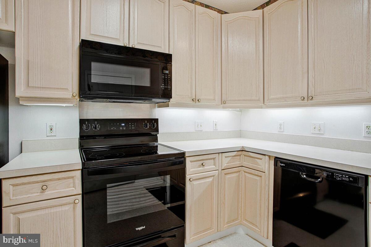 501 Runabout Loop, Unit 501 Solomons, MD 20688 - Photo 19 of 36 a kitchen with white cabinets and black appliances