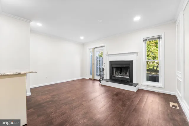an empty room with wooden floor a fireplace and windows