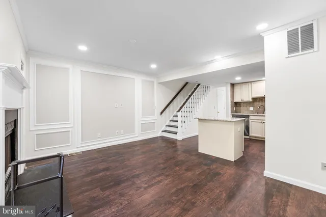 a view of an empty room with wooden floor and stairs