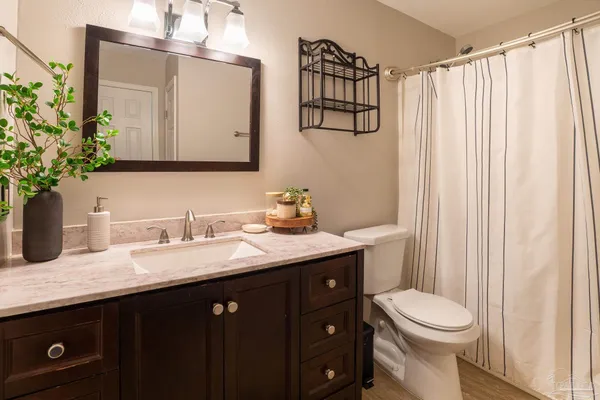 a bathroom with a granite countertop sink vanity mirror and toilet