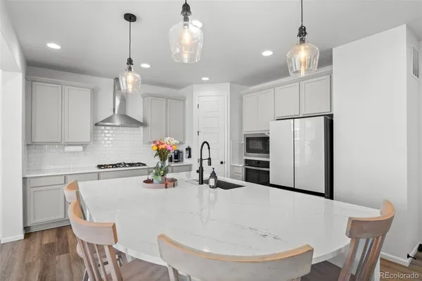 a kitchen with stainless steel appliances a dining table chairs and white cabinets