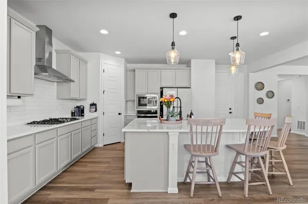 a kitchen with stainless steel appliances kitchen island granite countertop a table chairs sink and cabinets