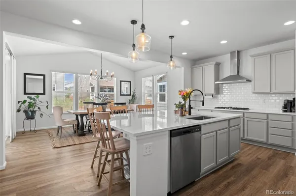 a kitchen with stainless steel appliances kitchen island granite countertop a table chairs sink and cabinets
