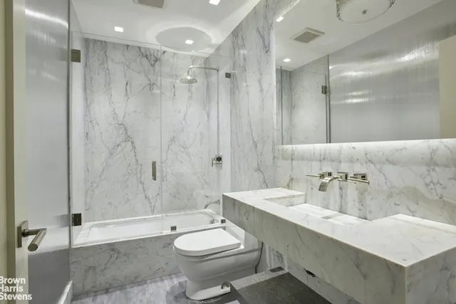 a bathroom with a sink a toilet a mirror and shower