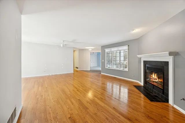 a view of an empty room with wooden floor fireplace and a window