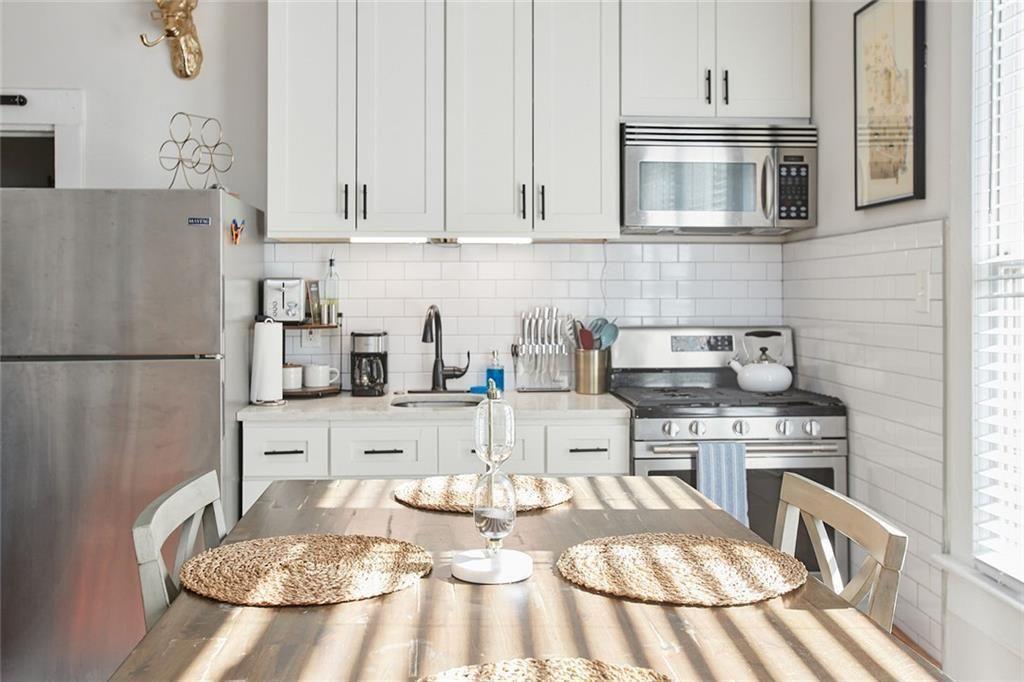887 Myrtle Street Northeast Atlanta, GA 30309 - Photo 6 of 27 a kitchen with stainless steel appliances kitchen island granite countertop a refrigerator a stove a sink and white cabinets with wooden floor