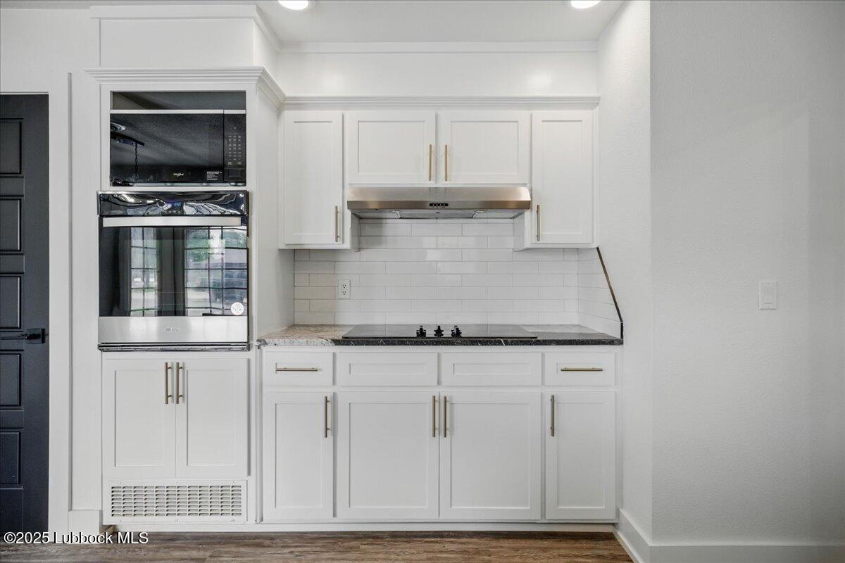 4214 64th Street Lubbock, TX 79413 - Photo 11 of 32 a kitchen with granite countertop a stove a microwave and wooden cabinets