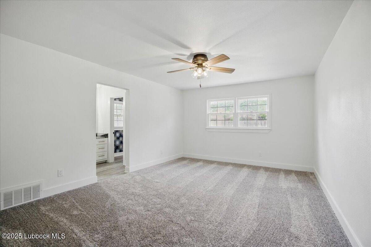4214 64th Street Lubbock, TX 79413 - Photo 16 of 32 an empty room with windows and chandelier fan