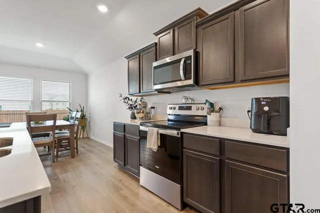 a kitchen with stainless steel appliances granite countertop a sink dishwasher stove and microwave with wooden floor