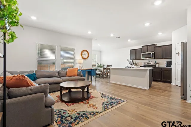 a living room with stainless steel appliances furniture and a kitchen view