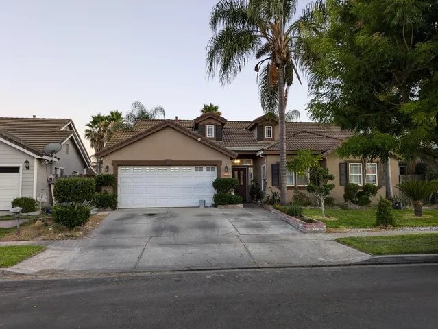 a front view of a house with a garden and trees