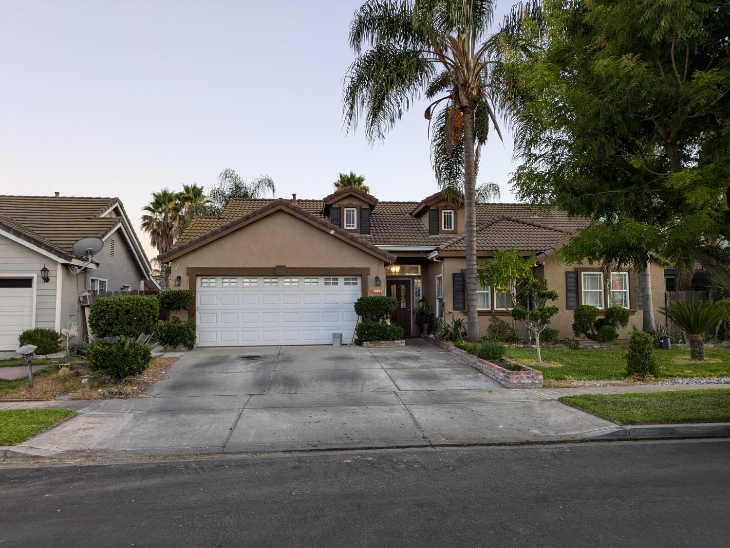 a front view of a house with a garden and trees