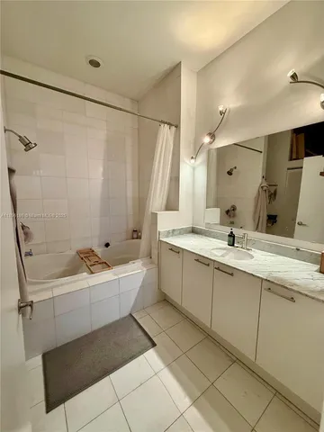 a bathroom with a tub sink mirror and a shower