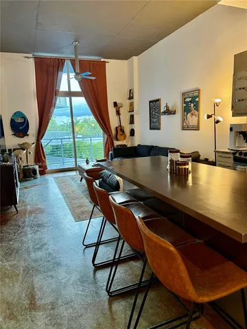 a living room with table chairs and a floor to ceiling window
