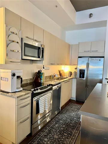 a kitchen with granite countertop white cabinets and stainless steel appliances