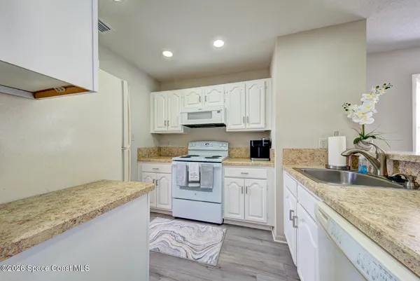 a kitchen with granite countertop white cabinets and white appliances