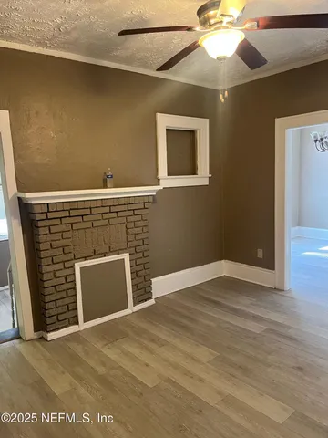 a view of an empty room with window and wooden floor