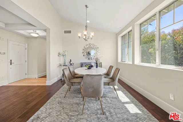 a dining room with wooden floor a chandelier a wooden table and chairs