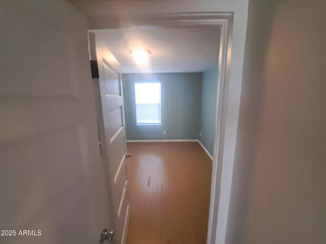 a view of hallway with window and wooden floor
