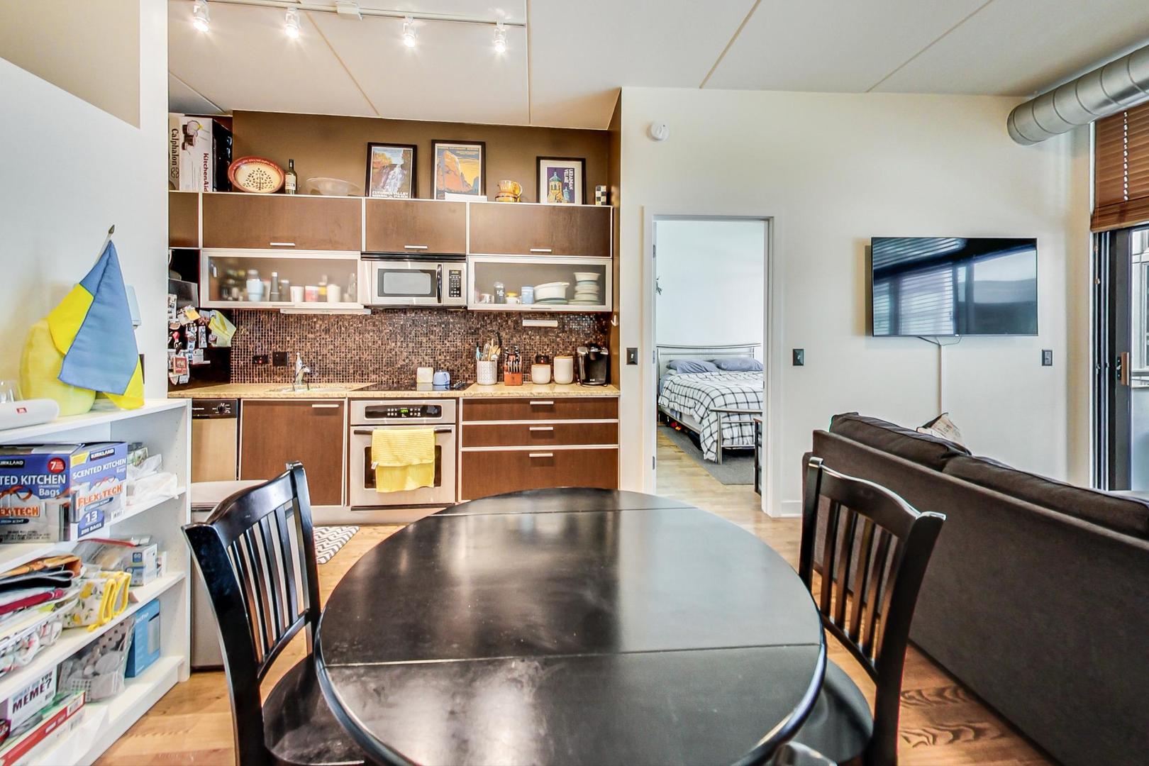 660 West Wayman Street, Unit 603 Chicago, IL 60661 - Photo 6 of 31 a kitchen with stainless steel appliances granite countertop a stove top oven a dining table and chairs with wooden floor
