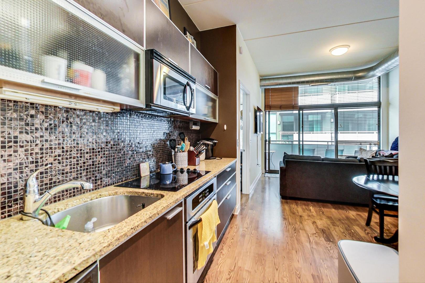 660 West Wayman Street, Unit 603 Chicago, IL 60661 - Photo 8 of 31 a kitchen with stainless steel appliances granite countertop a sink a stove and a wooden floors