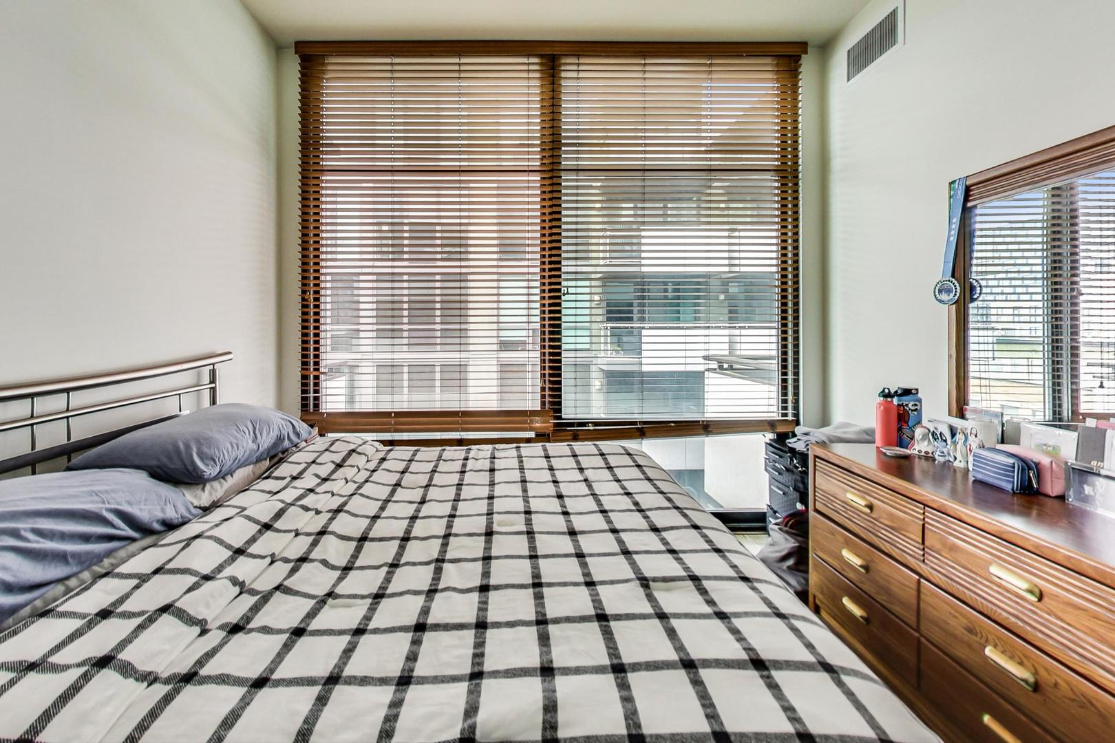 660 West Wayman Street, Unit 603 Chicago, IL 60661 - Photo 10 of 31 a bedroom with a large bed and a lamp on dresser
