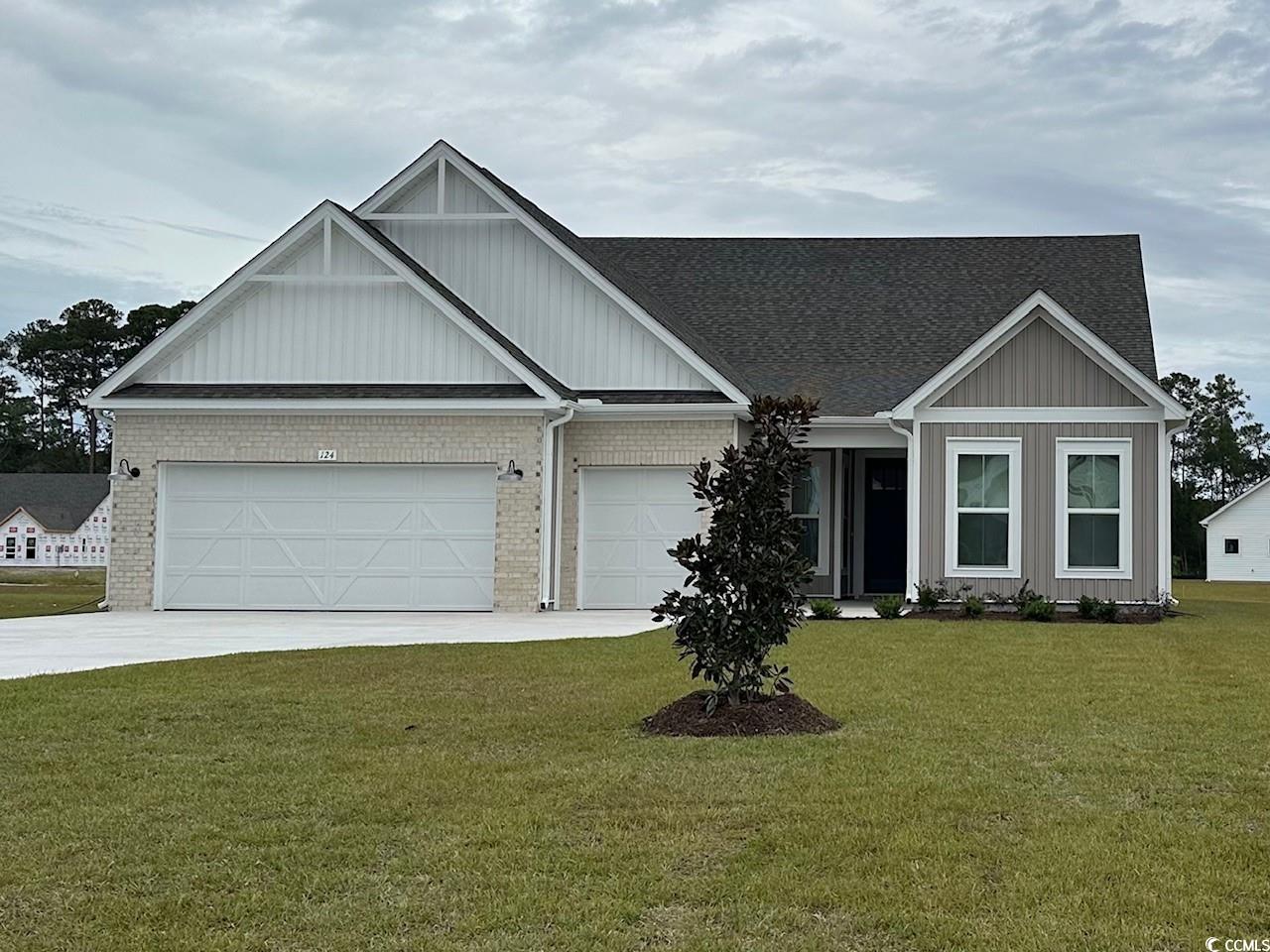 124 Northbrook Drive Murrells Inlet, SC 29576 - Photo 1 of 39 View of front facade featuring concrete driveway, board and batten siding, a lawn, brick siding, and a garage