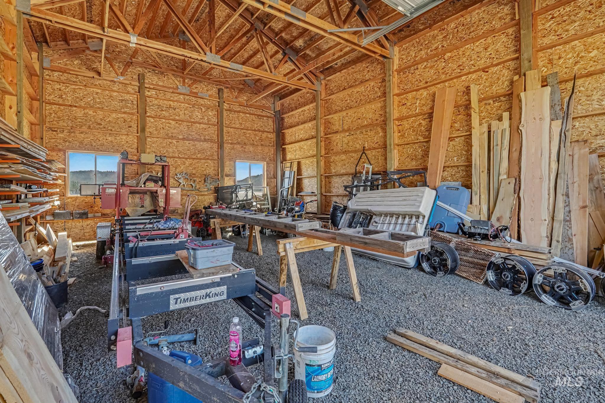 106 Wilderness Lake Road Cascade, ID 83611 - Photo 30 of 35 Barn interior featuring an exposed wood beam ceiling, wood-paneled walls, two windows, and a gravel floor