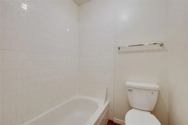 a white toilet sitting next to a white bath tub